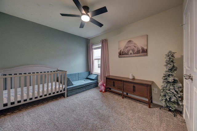 bedroom featuring a nursery area, ceiling fan, and carpet flooring