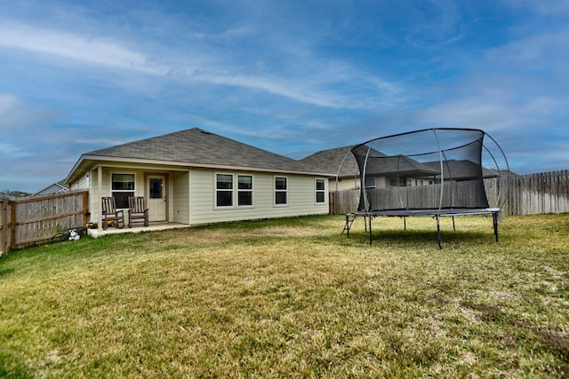 back of property featuring a trampoline, a lawn, and a patio area