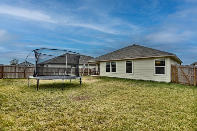 back of house with a trampoline and a lawn