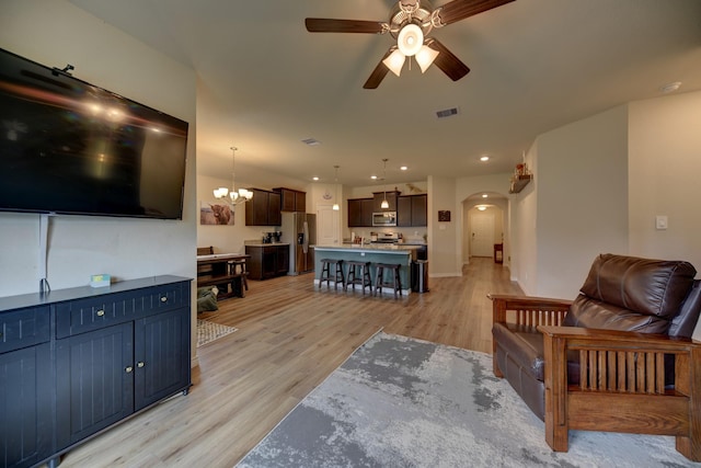 living room with ceiling fan with notable chandelier and light wood-type flooring