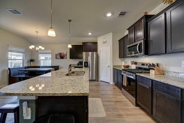 kitchen with sink, decorative light fixtures, an island with sink, stainless steel appliances, and light hardwood / wood-style floors