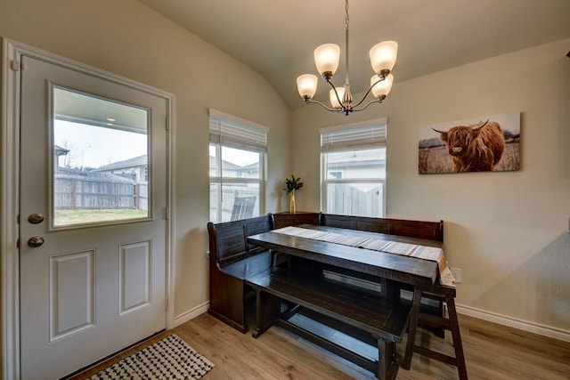 dining room featuring vaulted ceiling, an inviting chandelier, and light hardwood / wood-style flooring