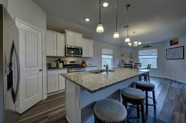 kitchen featuring sink, white cabinetry, hanging light fixtures, appliances with stainless steel finishes, and a kitchen island with sink