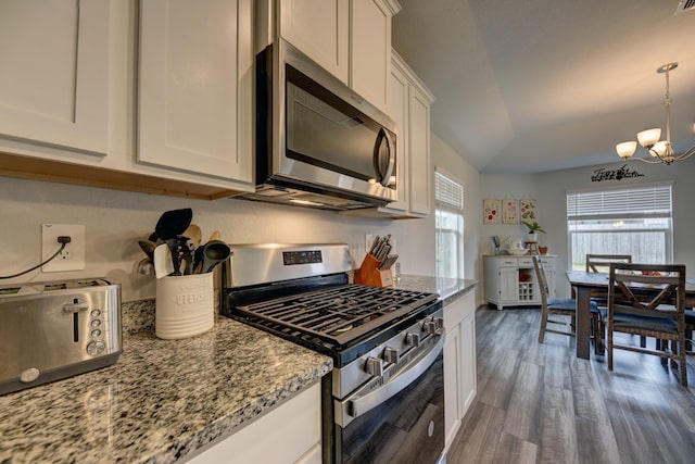 kitchen featuring vaulted ceiling, appliances with stainless steel finishes, dark hardwood / wood-style floors, light stone countertops, and white cabinets