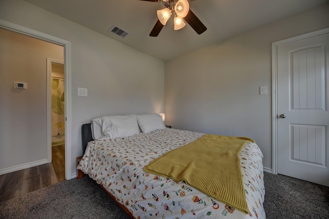 bedroom featuring dark hardwood / wood-style flooring, ensuite bath, and ceiling fan