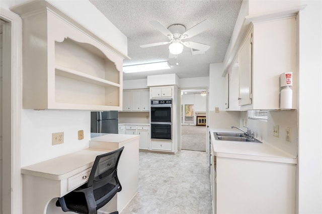 kitchen featuring sink, ceiling fan, black appliances, a textured ceiling, and white cabinets