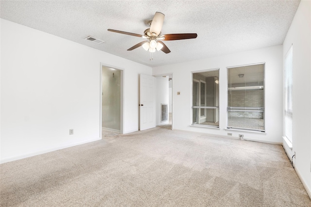 carpeted empty room with ceiling fan and a textured ceiling