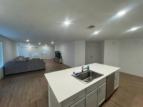 kitchen with dishwasher, a kitchen island with sink, sink, and dark wood-type flooring