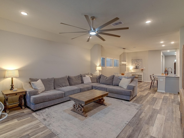 living room featuring ceiling fan, sink, and light hardwood / wood-style floors