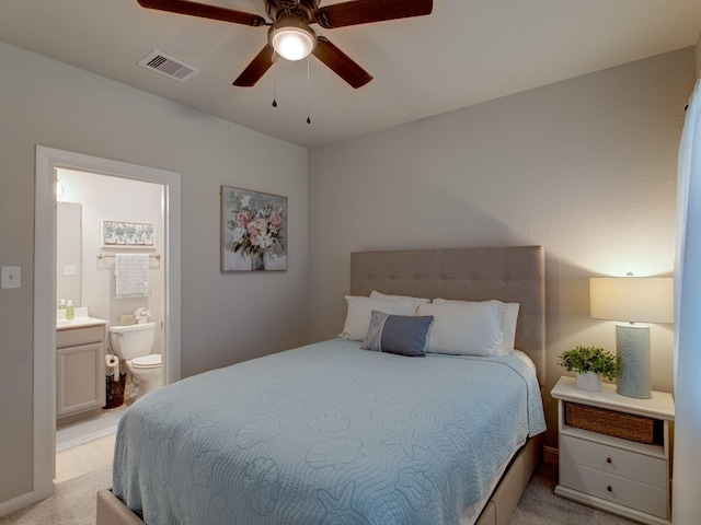 bedroom with connected bathroom, light colored carpet, and ceiling fan