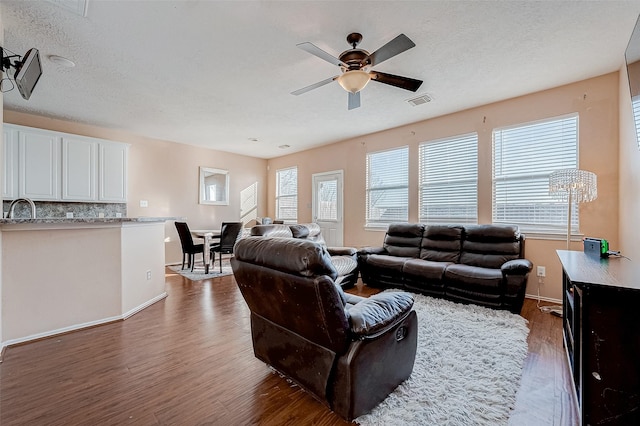 living room with sink, a textured ceiling, dark hardwood / wood-style floors, and ceiling fan