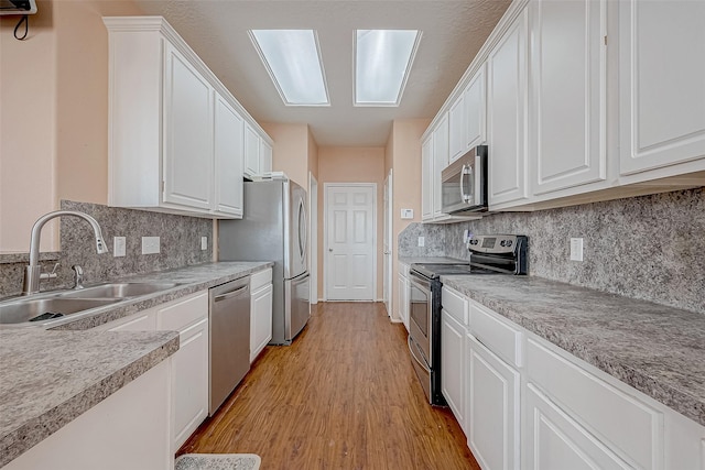 kitchen with white cabinetry, appliances with stainless steel finishes, sink, and light hardwood / wood-style flooring