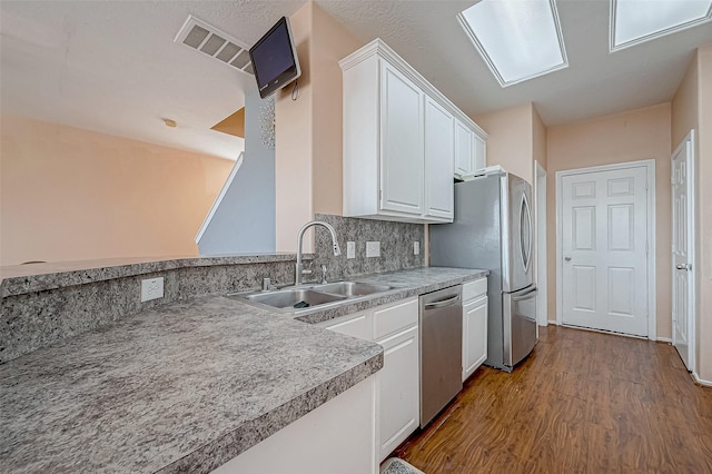 kitchen with sink, white cabinetry, stainless steel appliances, decorative backsplash, and light wood-type flooring