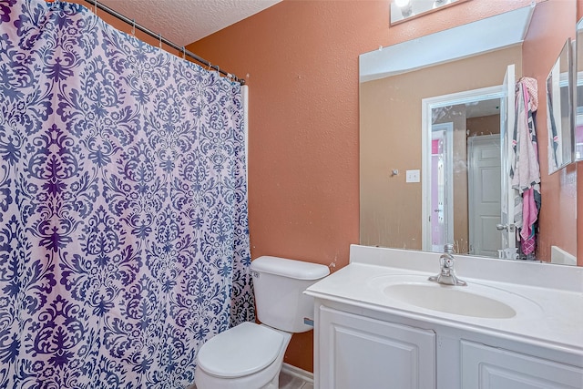 bathroom with vanity, toilet, and a textured ceiling