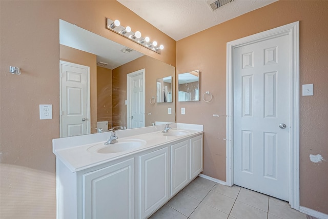 bathroom with vanity, toilet, tile patterned flooring, and a textured ceiling