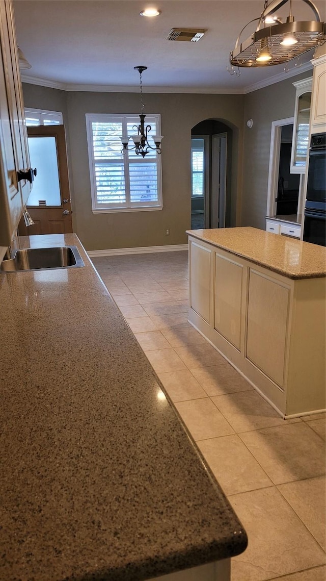 kitchen with hanging light fixtures, light tile patterned flooring, a kitchen island, and sink