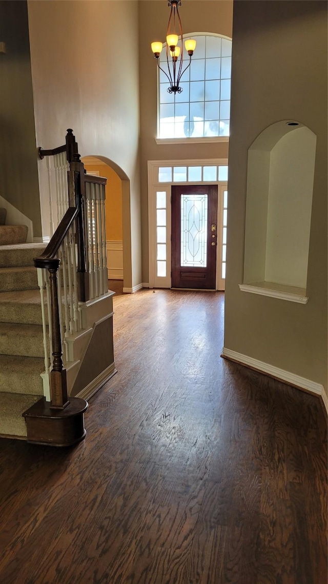 foyer with an inviting chandelier, wood-type flooring, and a high ceiling