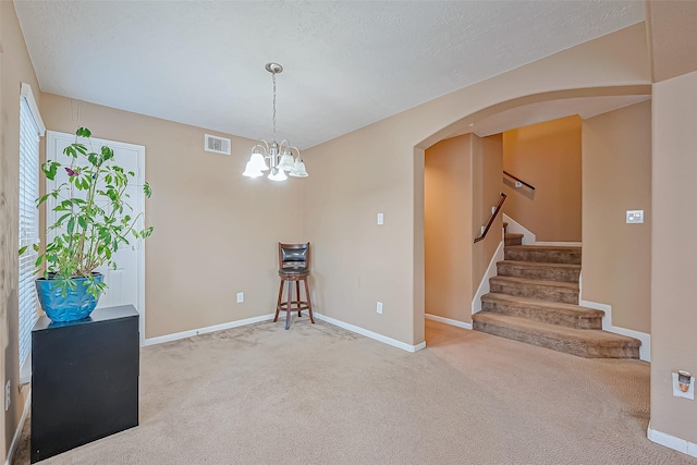 unfurnished room featuring carpet floors, a chandelier, and a textured ceiling