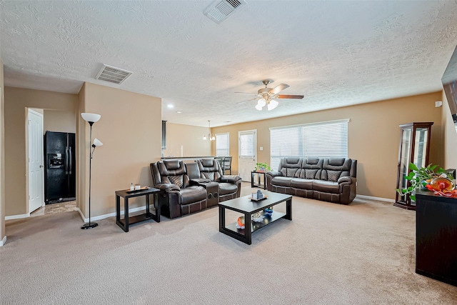 living room featuring ceiling fan, light colored carpet, and a textured ceiling