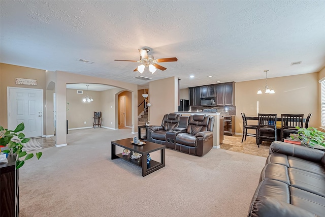 carpeted living room with ceiling fan with notable chandelier and a textured ceiling