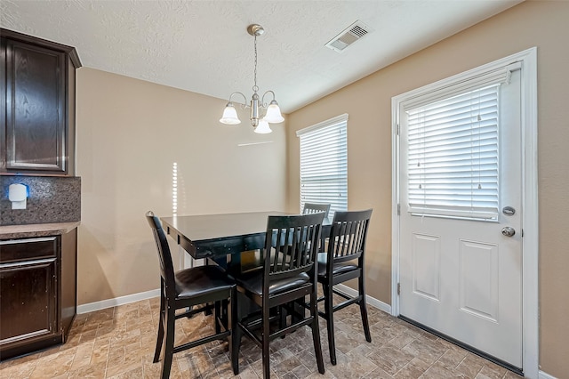 dining space featuring an inviting chandelier and a textured ceiling