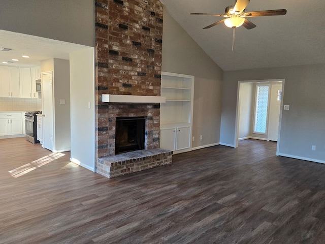 unfurnished living room with a brick fireplace, dark wood-type flooring, high vaulted ceiling, and ceiling fan