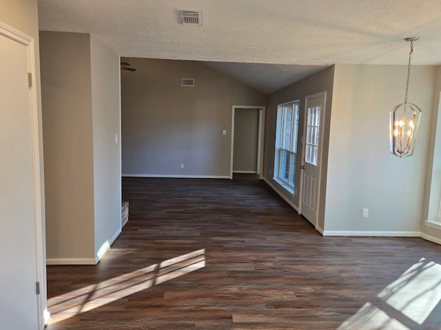 spare room with lofted ceiling, a notable chandelier, dark hardwood / wood-style floors, and a textured ceiling