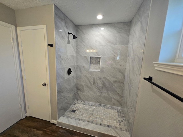 bathroom with hardwood / wood-style flooring, tiled shower, and a textured ceiling