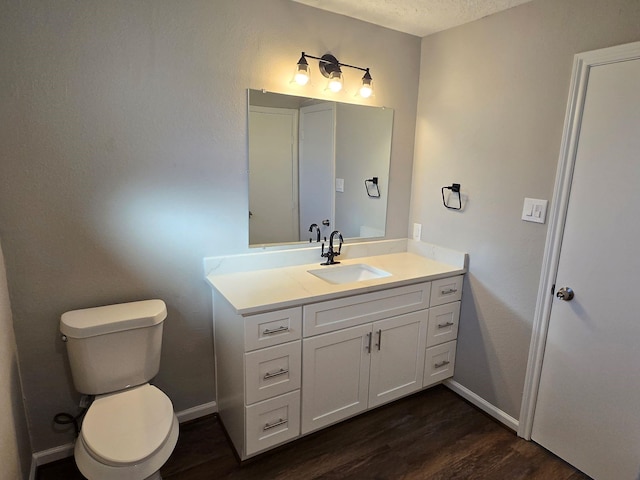 bathroom featuring vanity, wood-type flooring, toilet, and a textured ceiling