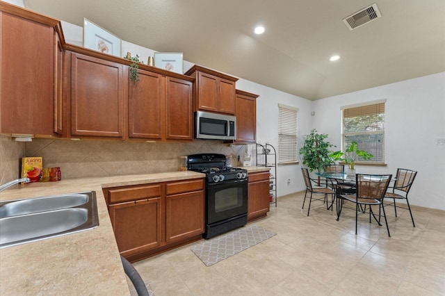 kitchen with tasteful backsplash, lofted ceiling, sink, and gas stove