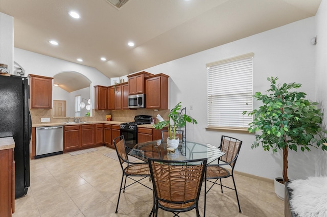 kitchen featuring lofted ceiling, sink, tasteful backsplash, black appliances, and light tile patterned flooring