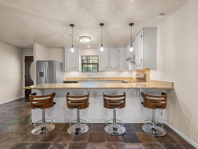 kitchen with stainless steel fridge, kitchen peninsula, electric stove, light stone countertops, and white cabinets