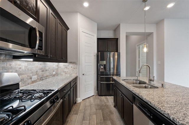 kitchen featuring sink, light stone countertops, light hardwood / wood-style floors, and appliances with stainless steel finishes