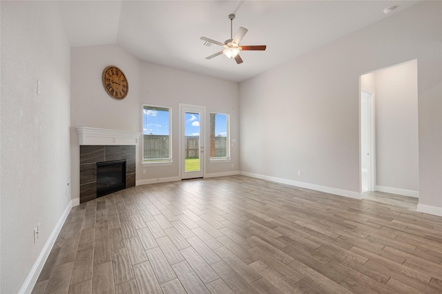 unfurnished living room with vaulted ceiling, ceiling fan, a fireplace, and light hardwood / wood-style floors