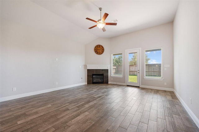 unfurnished living room featuring ceiling fan, lofted ceiling, dark hardwood / wood-style flooring, and a tiled fireplace