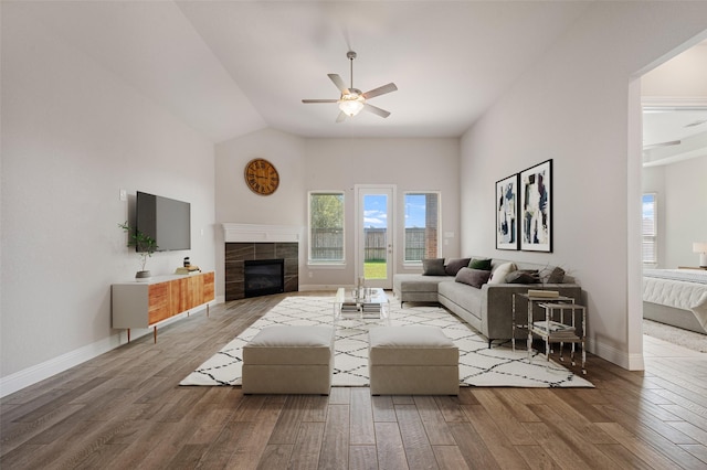 living room featuring ceiling fan, wood-type flooring, a fireplace, and lofted ceiling