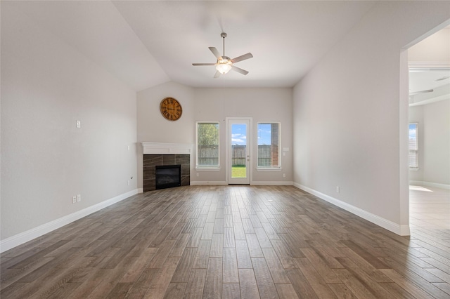 unfurnished living room with dark wood-type flooring, ceiling fan, lofted ceiling, and a tile fireplace