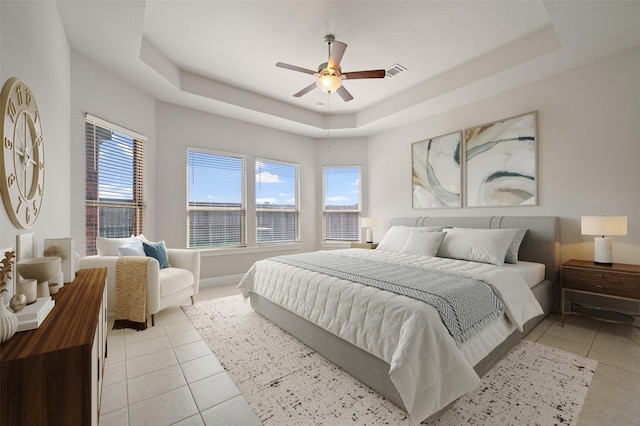 tiled bedroom with ceiling fan and a raised ceiling