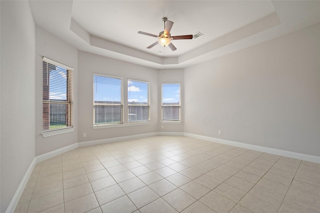 tiled spare room with ceiling fan and a raised ceiling