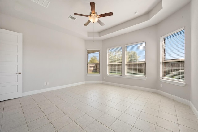 tiled spare room featuring ceiling fan and a tray ceiling