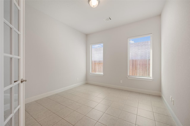 unfurnished room featuring light tile patterned flooring and french doors