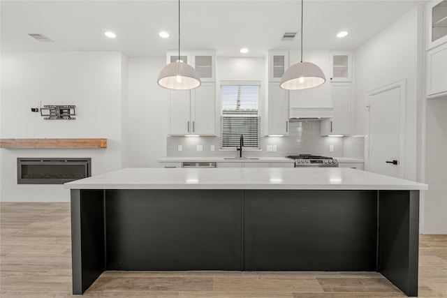 kitchen featuring white cabinetry, sink, and hanging light fixtures