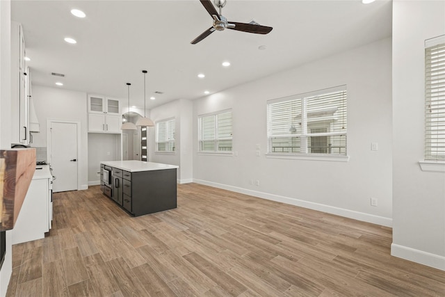 kitchen with pendant lighting, white cabinets, a center island, ceiling fan, and light hardwood / wood-style flooring