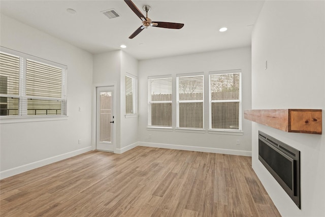 unfurnished living room featuring ceiling fan and light wood-type flooring