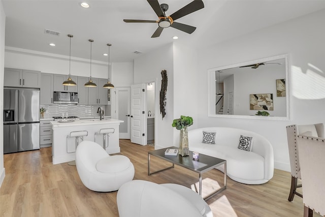 living room featuring sink, ceiling fan, and light hardwood / wood-style flooring