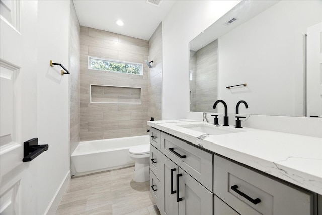 full bathroom with tiled shower / bath, vanity, and toilet