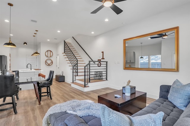 living room with ceiling fan, sink, and light hardwood / wood-style floors