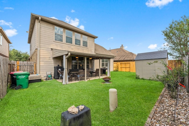 rear view of house featuring a patio, an outdoor fire pit, a shed, and a lawn