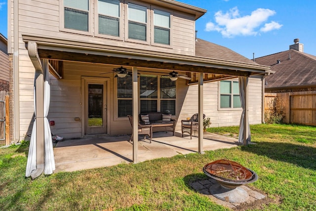 rear view of house with ceiling fan, an outdoor fire pit, a yard, and a patio area