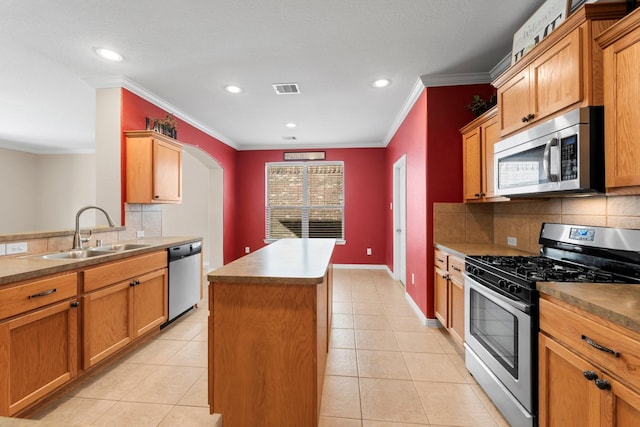 kitchen featuring stainless steel appliances, tasteful backsplash, a kitchen island, and sink